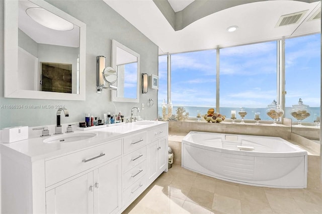 bathroom with a bathtub, a water view, tile patterned floors, and vanity