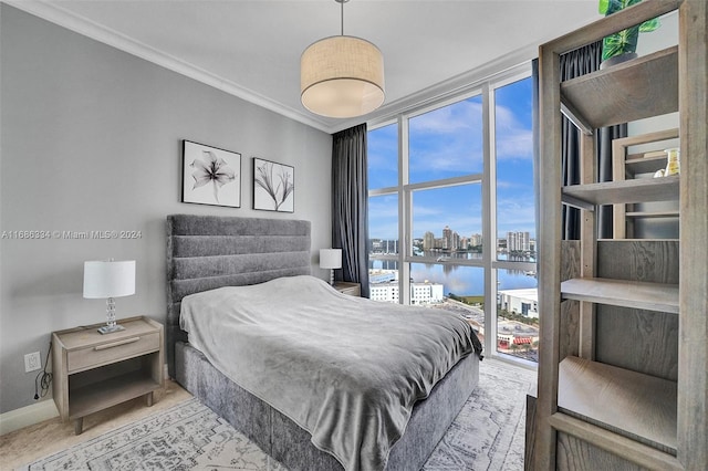 bedroom featuring a water view, crown molding, and expansive windows