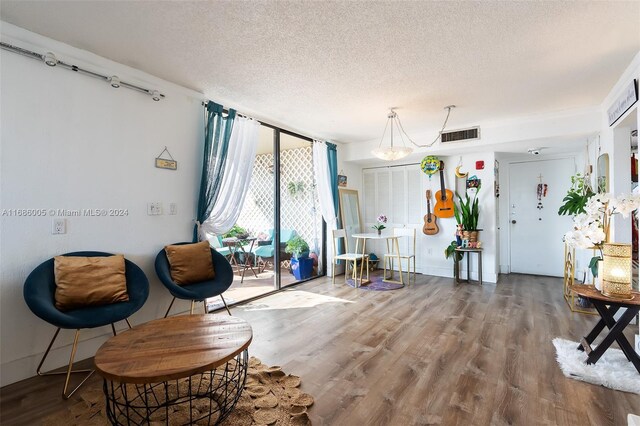 living area featuring a textured ceiling, visible vents, and wood finished floors