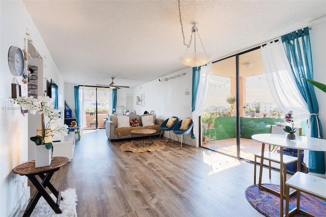 living room featuring a textured ceiling, a wall of windows, wood-type flooring, and ceiling fan