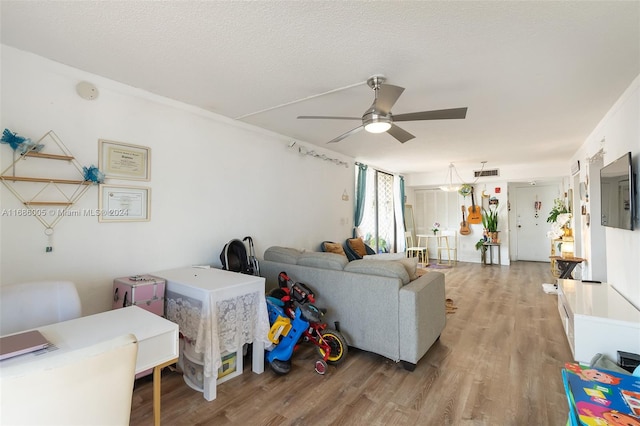 living room featuring light hardwood / wood-style flooring, a textured ceiling, and ceiling fan