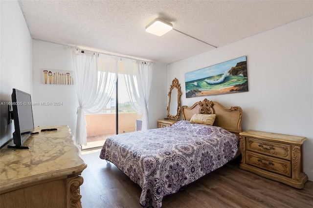 bedroom with dark wood-type flooring, access to outside, and a textured ceiling