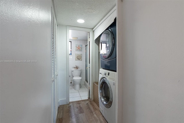 laundry area featuring laundry area, stacked washer / dryer, wood finished floors, and a textured ceiling