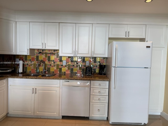 kitchen featuring white cabinets, tasteful backsplash, dark stone countertops, sink, and white appliances