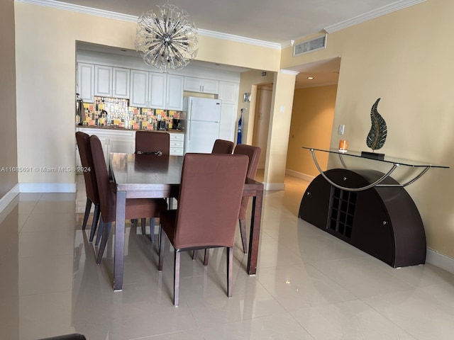 tiled dining space featuring a notable chandelier and ornamental molding