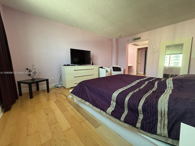 bedroom featuring light hardwood / wood-style flooring and a textured ceiling