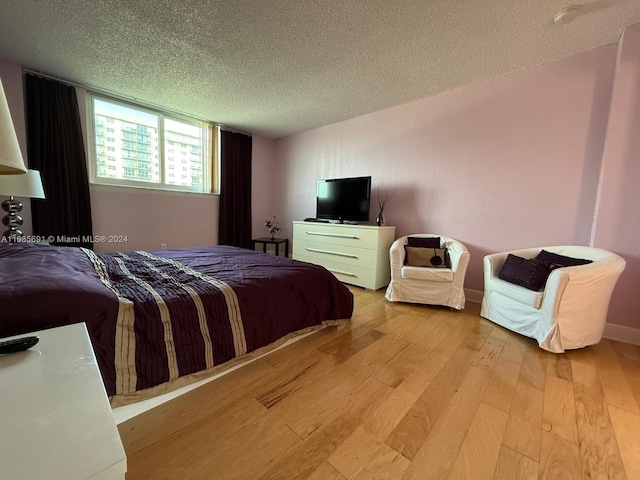 bedroom with a textured ceiling and light wood-type flooring