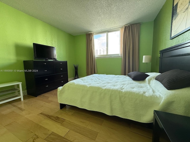 bedroom with a textured ceiling and light hardwood / wood-style floors