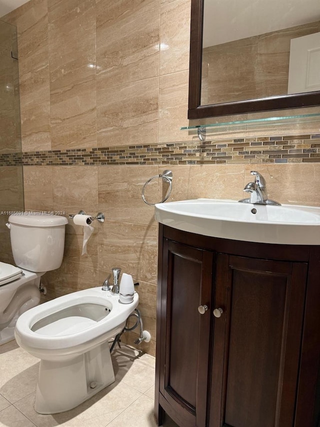 bathroom featuring toilet, vanity, a bidet, and tile walls