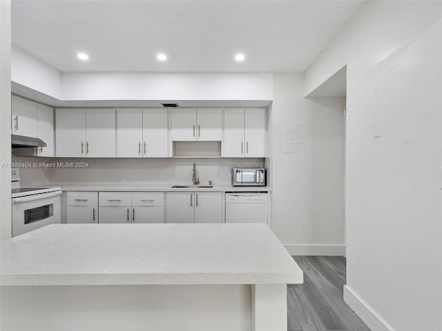 kitchen featuring white cabinetry, sink, tasteful backsplash, white appliances, and light wood-type flooring