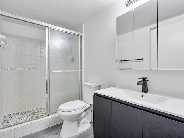 bathroom with toilet, an enclosed shower, vanity, and wood-type flooring