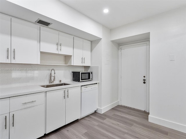 kitchen featuring light hardwood / wood-style floors, white dishwasher, white cabinets, sink, and tasteful backsplash