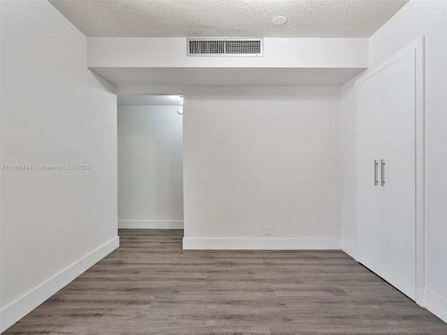 empty room with dark wood-type flooring and a textured ceiling