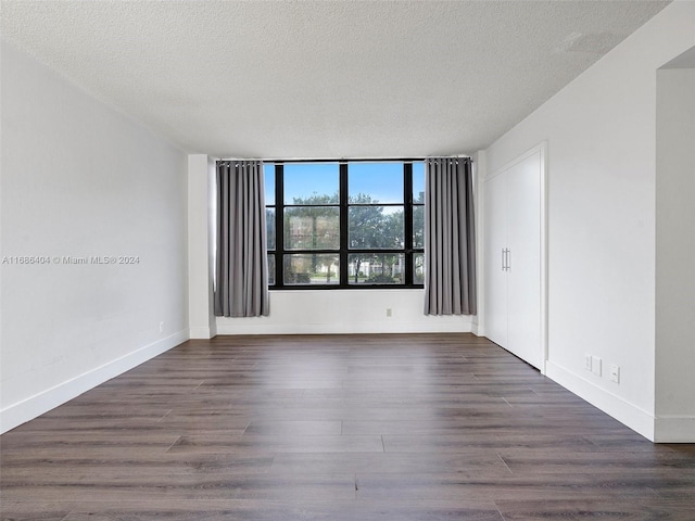 empty room featuring dark wood-type flooring and a textured ceiling