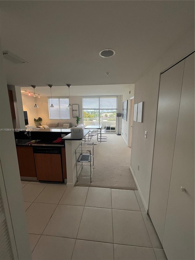 kitchen featuring light tile patterned floors, light carpet, visible vents, dishwasher, and decorative light fixtures