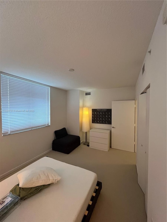 bedroom featuring a textured ceiling, mail area, carpet, and visible vents