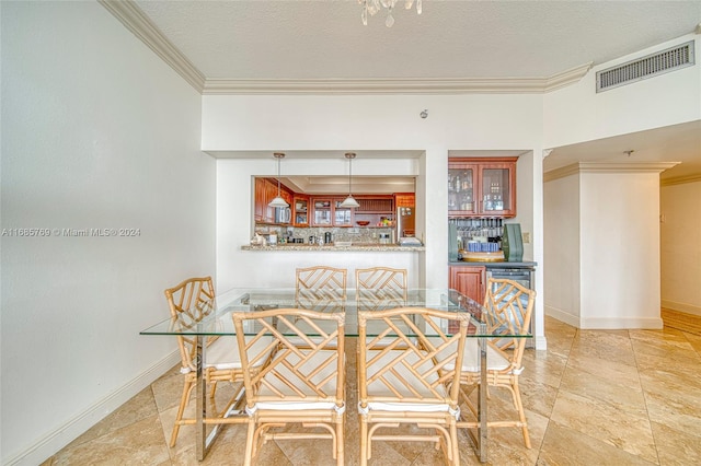 dining area with ornamental molding, bar, and a textured ceiling