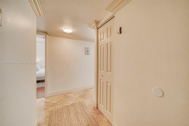 hall with ornamental molding, light tile patterned flooring, and a textured ceiling