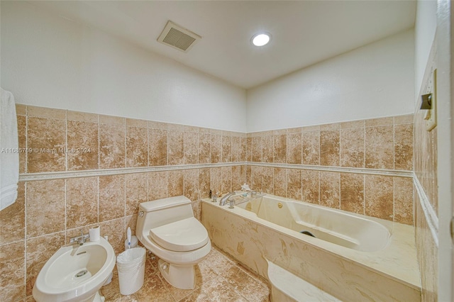 bathroom with a bathtub, tile walls, toilet, a bidet, and tile patterned flooring