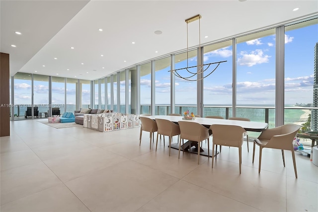 dining room with expansive windows, light tile patterned flooring, a water view, and an inviting chandelier