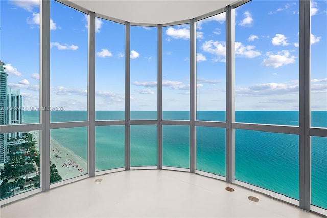 unfurnished sunroom with a water view and a beach view