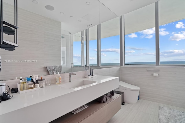 bathroom featuring tile walls, vanity, a water view, and toilet