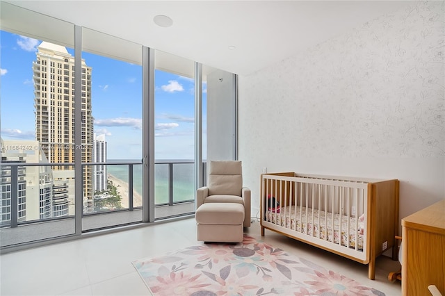 bedroom with a water view, expansive windows, multiple windows, and a nursery area