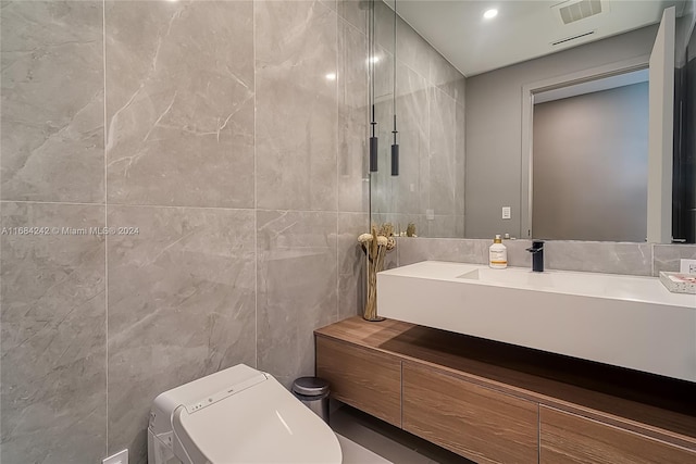 bathroom with vanity, toilet, and tile walls