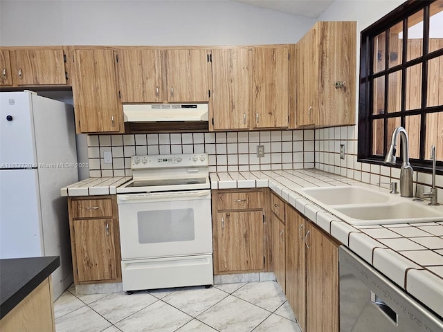 kitchen with sink, white appliances, backsplash, tile countertops, and vaulted ceiling