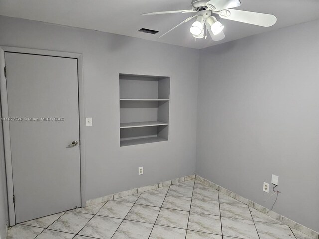 empty room with ceiling fan and built in shelves