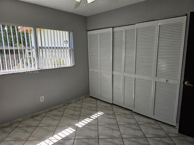 unfurnished bedroom featuring ceiling fan and a closet