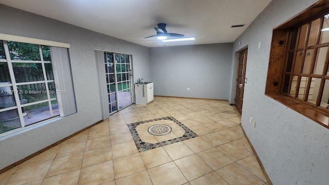 tiled spare room featuring ceiling fan and sink