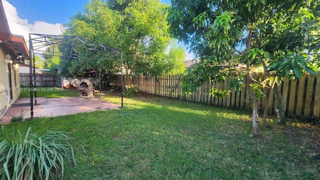 view of yard featuring an outdoor stone fireplace and a patio area