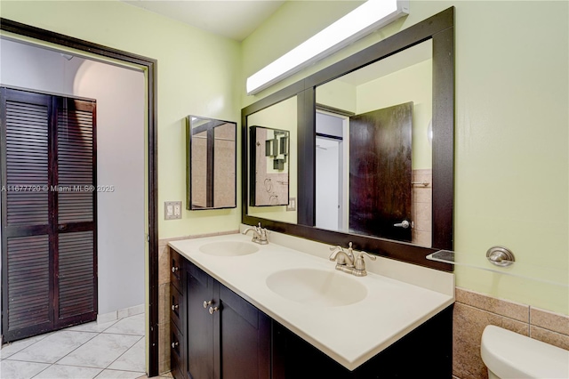 bathroom with double vanity, toilet, tile patterned floors, and a sink