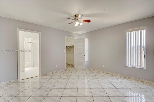 unfurnished bedroom with a walk in closet, light tile patterned floors, a ceiling fan, and a closet