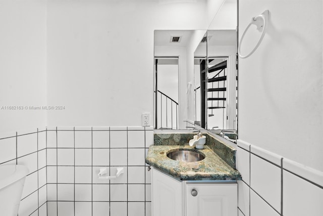 bathroom with tile walls, vanity, and toilet