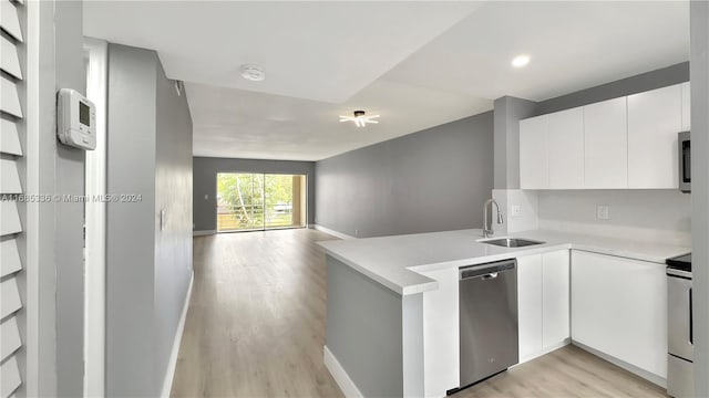 kitchen with sink, light wood-type flooring, kitchen peninsula, stainless steel appliances, and white cabinets