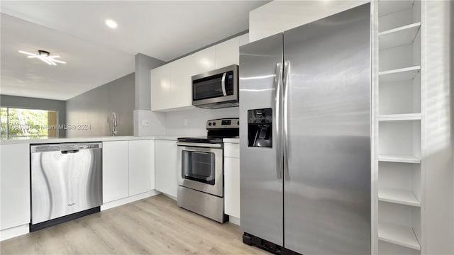 kitchen with light hardwood / wood-style floors, appliances with stainless steel finishes, sink, and white cabinets