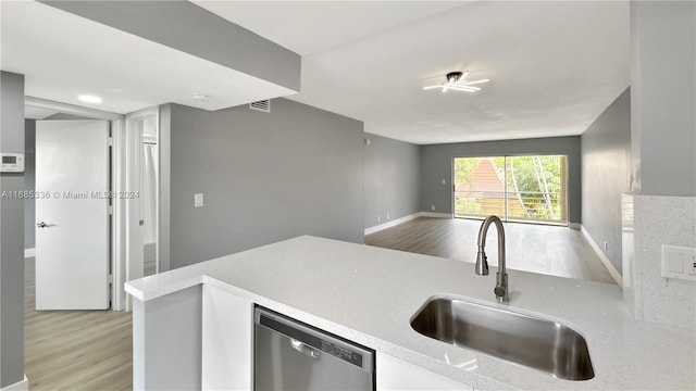 kitchen with kitchen peninsula, light stone countertops, dishwasher, light hardwood / wood-style floors, and sink