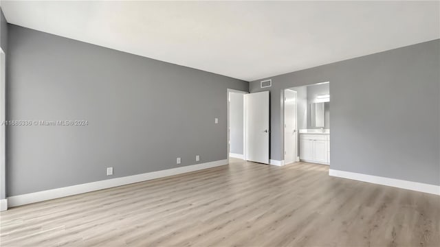 unfurnished bedroom with ensuite bathroom and light hardwood / wood-style flooring