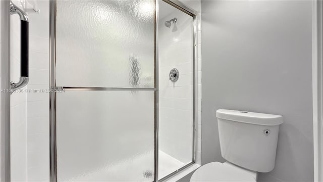 bathroom with a shower with door and toilet