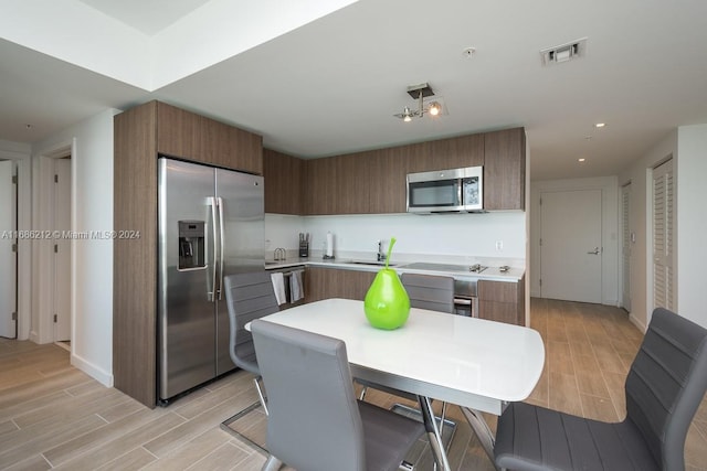 1600 SW 1st Ave Unit 1104, Miami, FL 33129 - kitchen featuring appliances with stainless steel finishes, wood finish floors, light countertops, brown cabinets, and recessed lighting