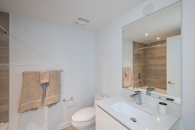 full bathroom with tiled shower / bath, vanity, and toilet