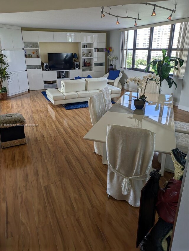 dining area with rail lighting and wood-type flooring