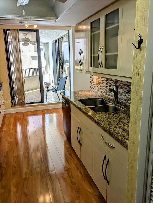 kitchen with hardwood / wood-style floors, plenty of natural light, dark stone counters, and sink