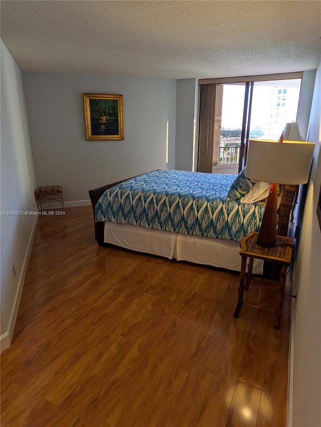 bedroom featuring access to outside, a textured ceiling, and hardwood / wood-style flooring