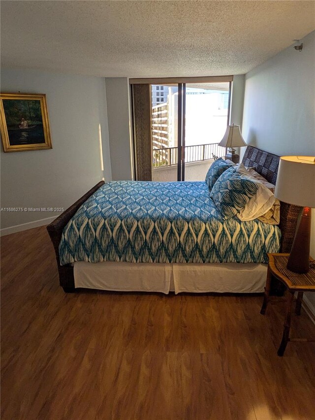 bedroom featuring access to exterior, hardwood / wood-style floors, and a textured ceiling