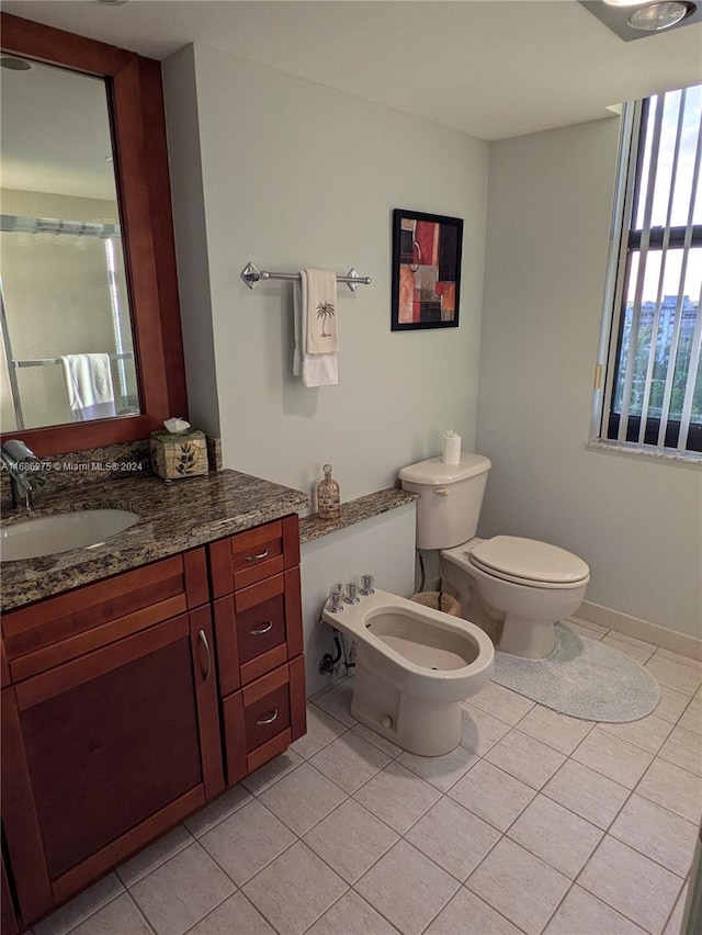 bathroom with tile patterned flooring, vanity, toilet, and a bidet