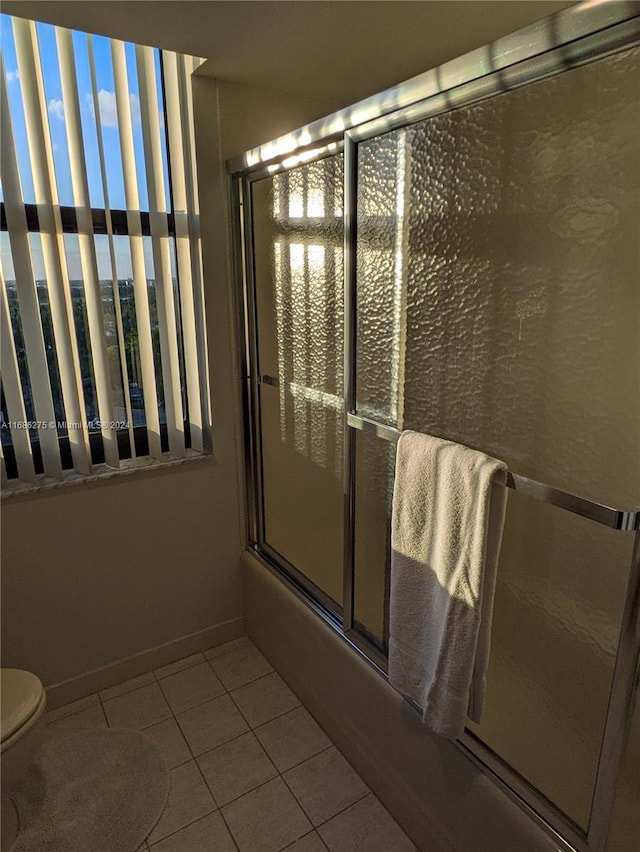 bathroom featuring tile patterned flooring, toilet, and enclosed tub / shower combo