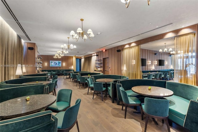 playroom featuring light hardwood / wood-style floors, a notable chandelier, and wooden walls